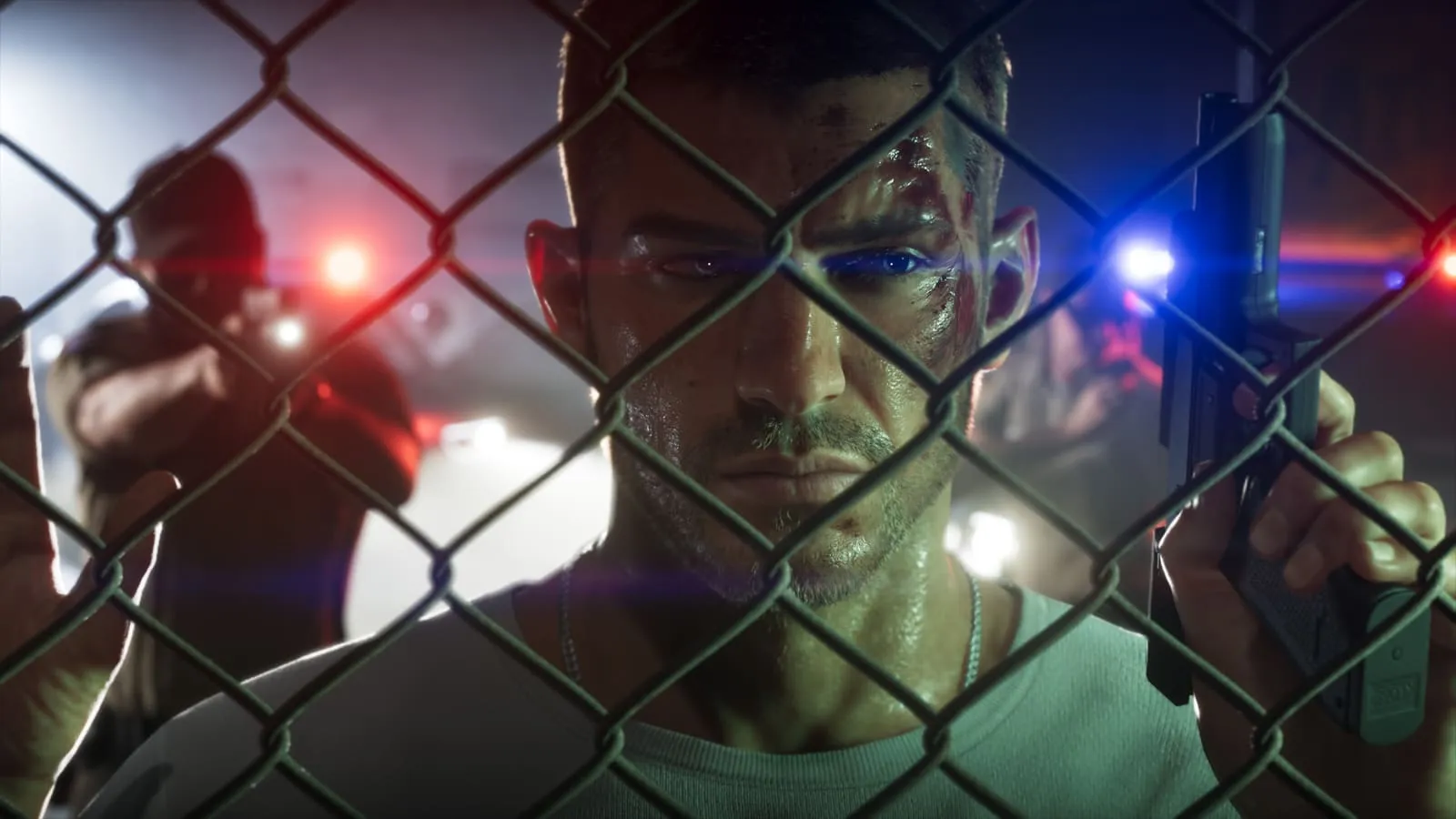 Behind a fence, with police lights behind him.