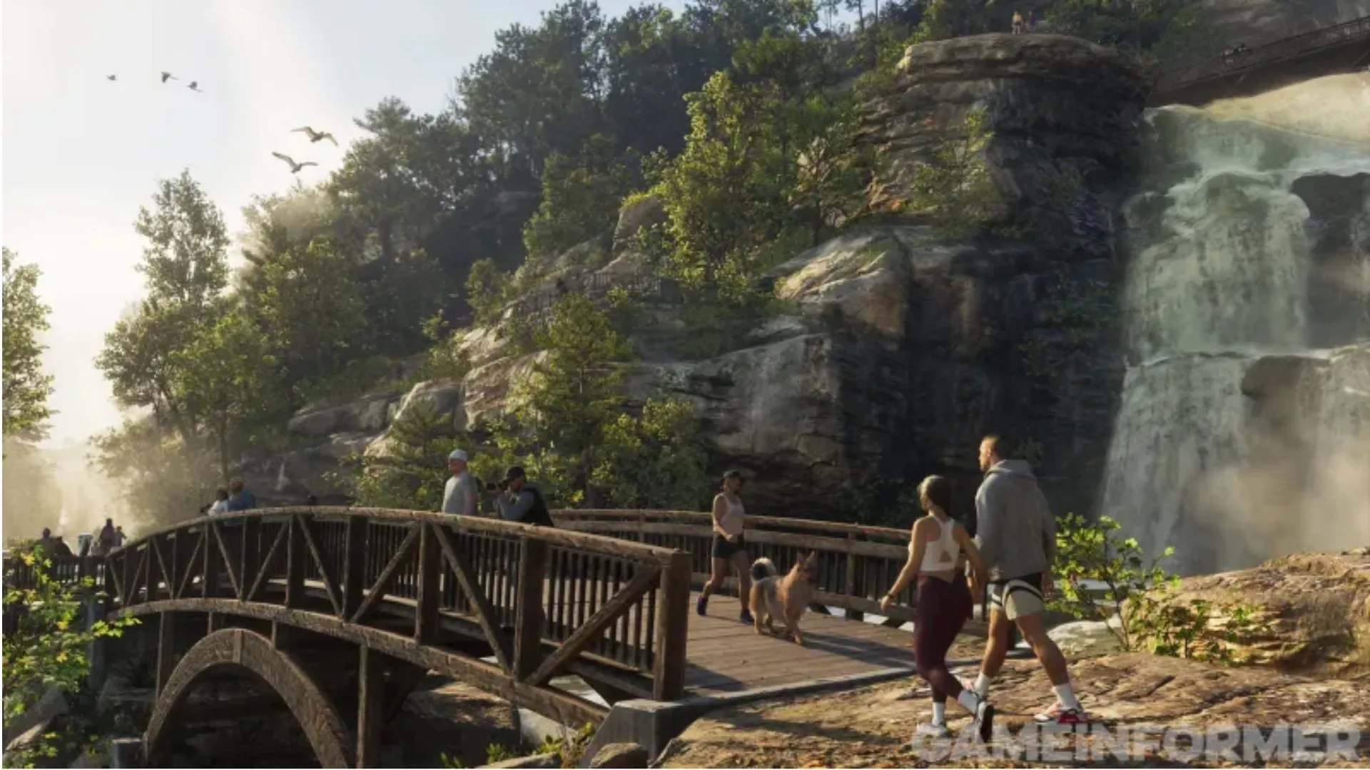 Several people and a dog cross a wooden bridge on a forest trail, beside a waterfall falling between rocks