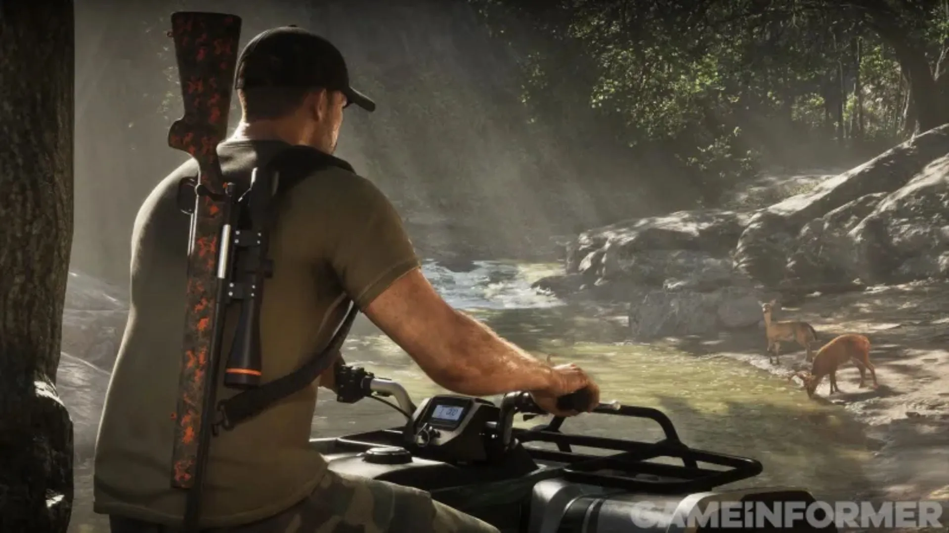 A man in a cap with a rifle on his back rides a quad bike through the woods, by a stream where two deer are drinking